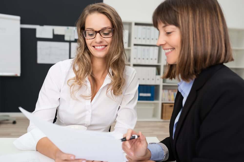 Close up Two Happy Young Businesswomen at the Office Talking About Business Report on Paper. (1)