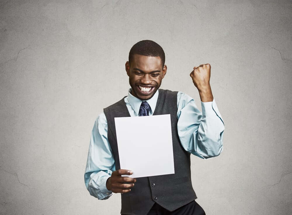 Closeup portrait happy excited young business man executive looking monthly statement glad to pay off bills isolated grey background. Positive emotion facial expression. Financial success good new (1)