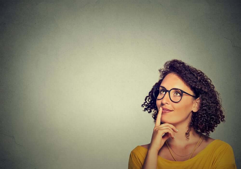 Portrait side profile happy beautiful woman thinking looking up isolated on grey wall background with copy space. Human face expressions, emotions, feelings, body language, perception (1)